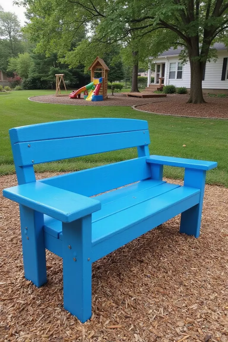A photo of a typical American home's garden with a bright blue bench made from recycled plastic lumber, placed near a children's play area on wood chips.