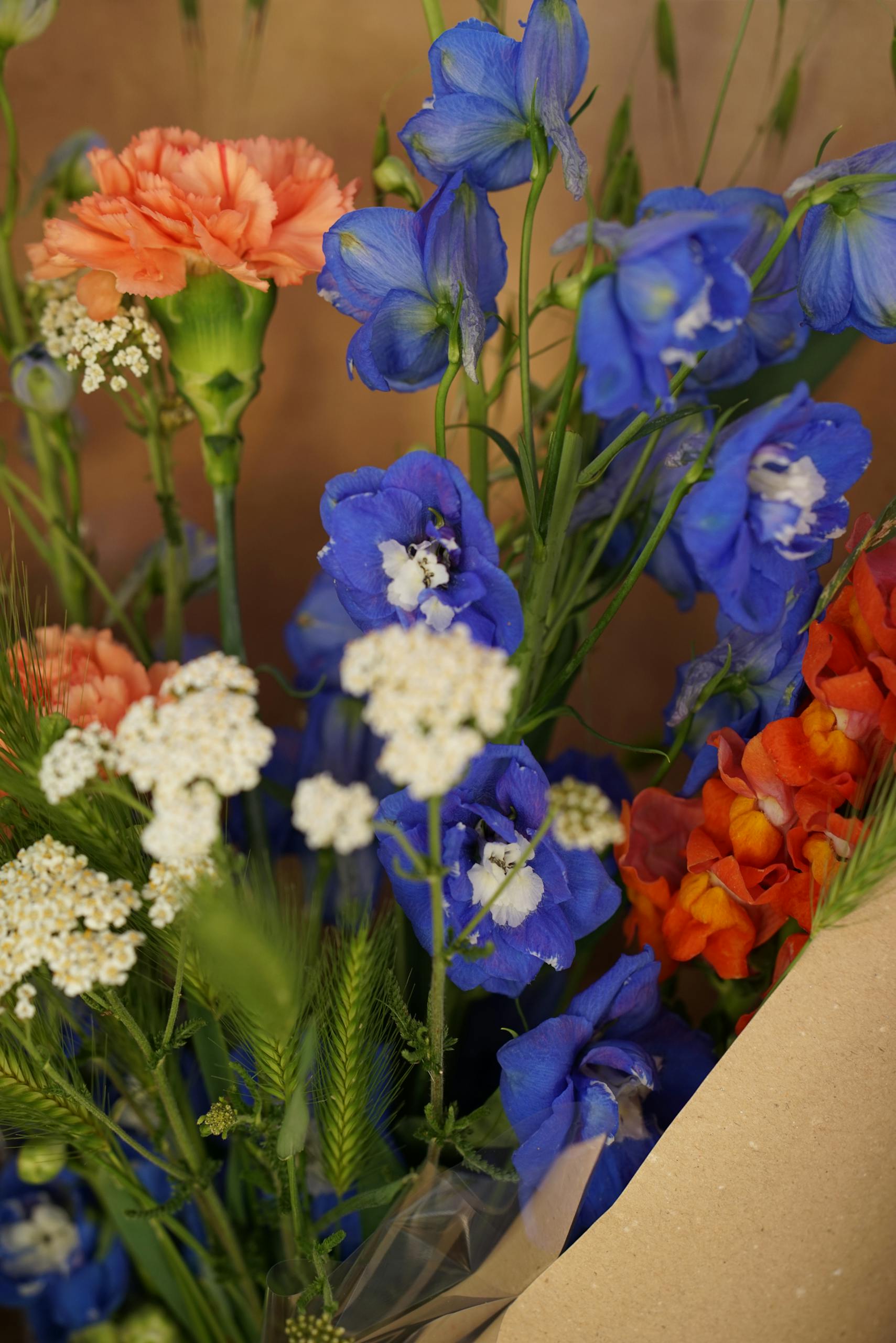 A close-up of a colorful bouquet with delphiniums, carnations, and yarrow flowers.